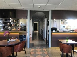 Un restaurante con barra, mostrador y zona de mesas y sillas.