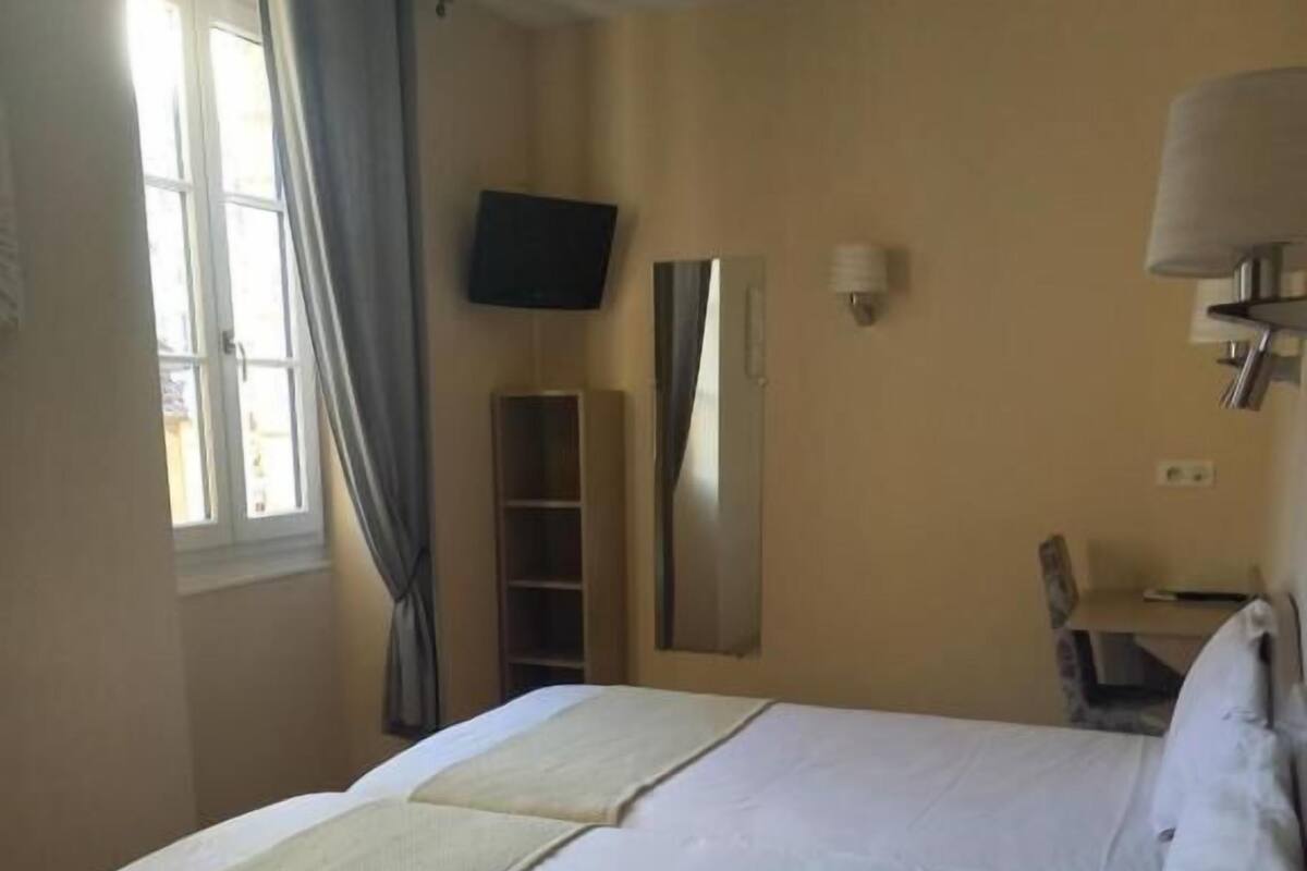 A hotel room with a bed, a TV, a mirror, a desk, and a chair.
