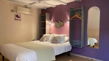 Un dormitorio con cama, armario, espejo y aire acondicionado de pared.