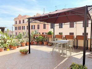 A covered outdoor seating area with potted plants, a table, and chairs. - HAUS OF LEMONS (Rome)