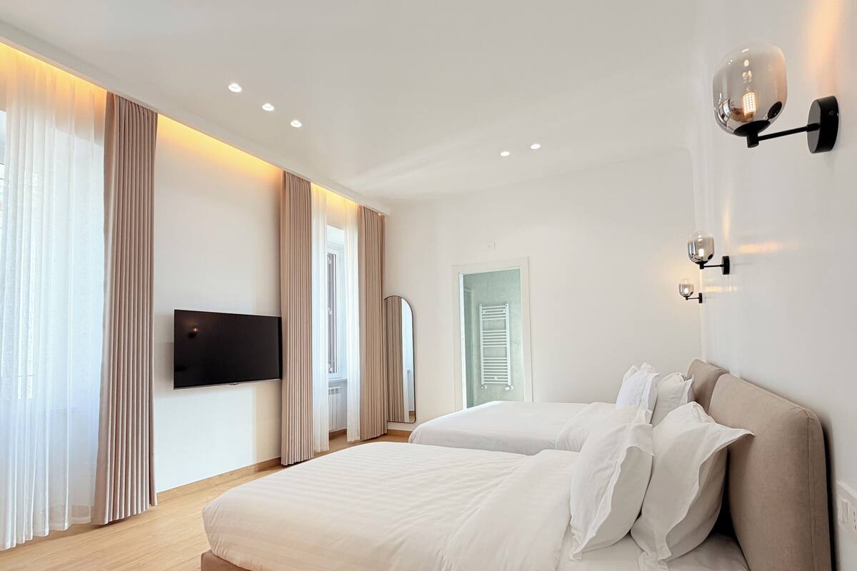 A modern hotel room with a large bed, a flat-screen TV, and a wall-mounted light fixture.