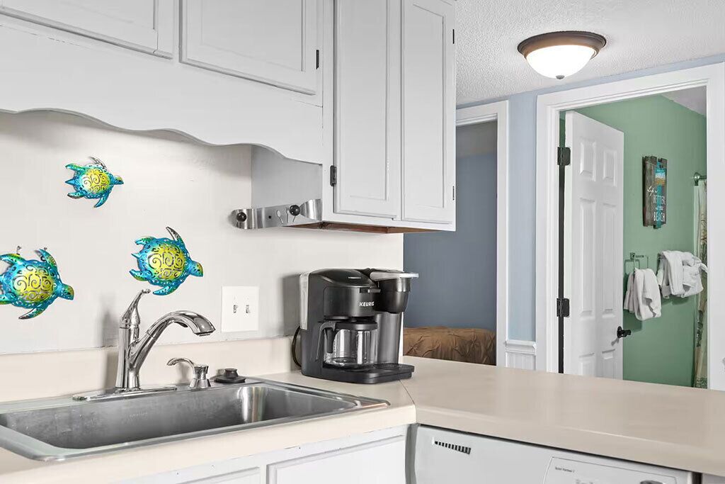 A kitchen with a coffee maker, a sink, and decorative wall art.