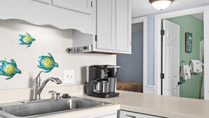 A kitchen with a coffee maker, a sink, and decorative wall art.