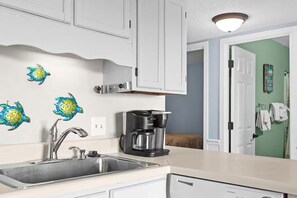 A kitchen with a coffee maker, a sink, and decorative wall art. - Myrtle's Finest (Myrtle Beach)