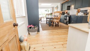 Een moderne keuken met donkere kastjes, een houten eettafel en een rieten mand.