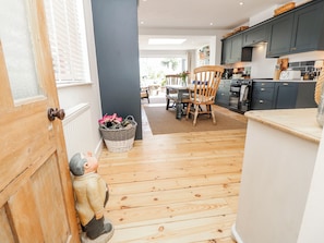 A modern kitchen with dark cabinets, a wooden dining table, and a wicker basket. - 4 Copse Lane (Freshwater)