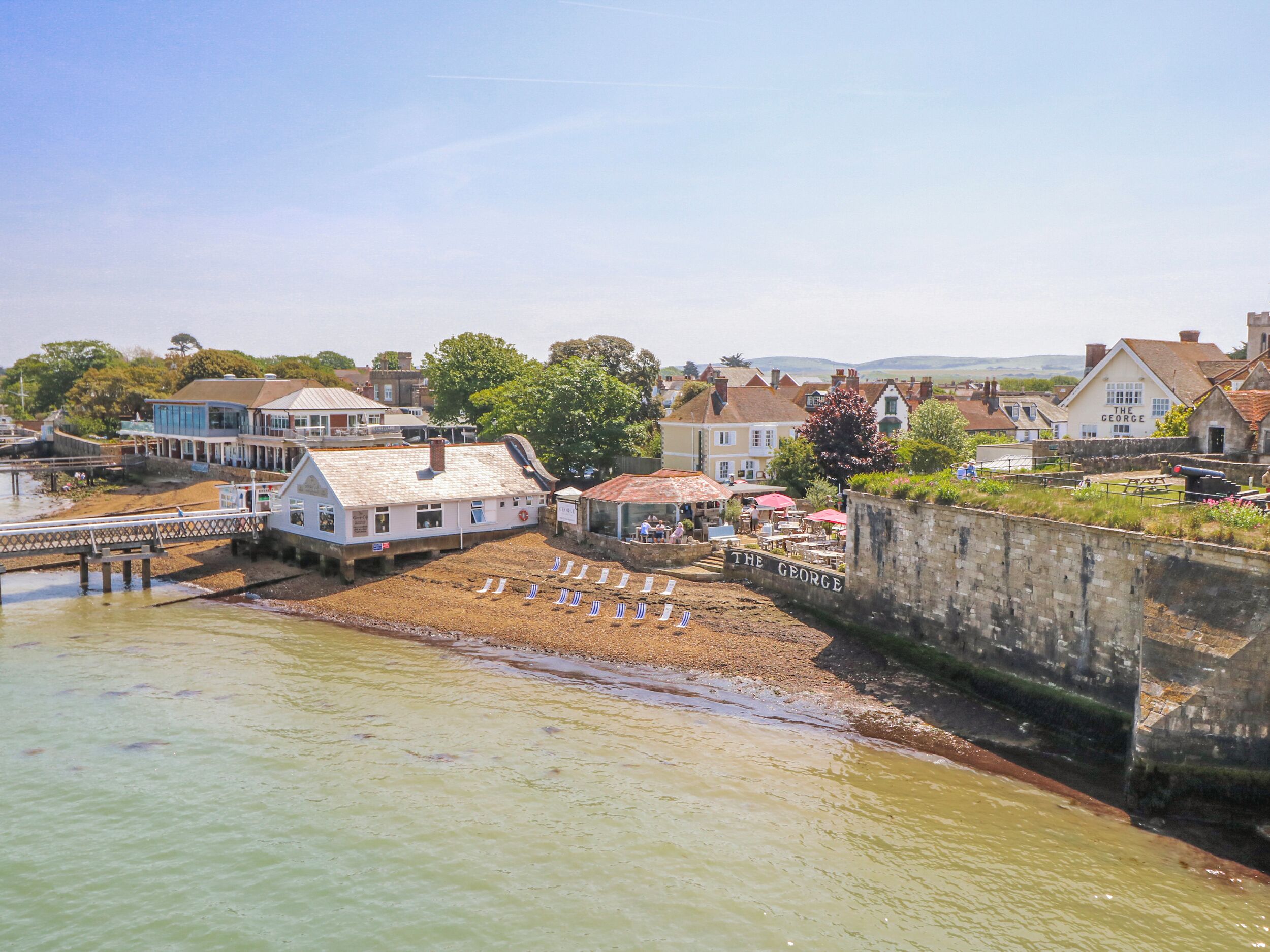 A coastal town with a pier, waterfront buildings, and a sandy beach area.
