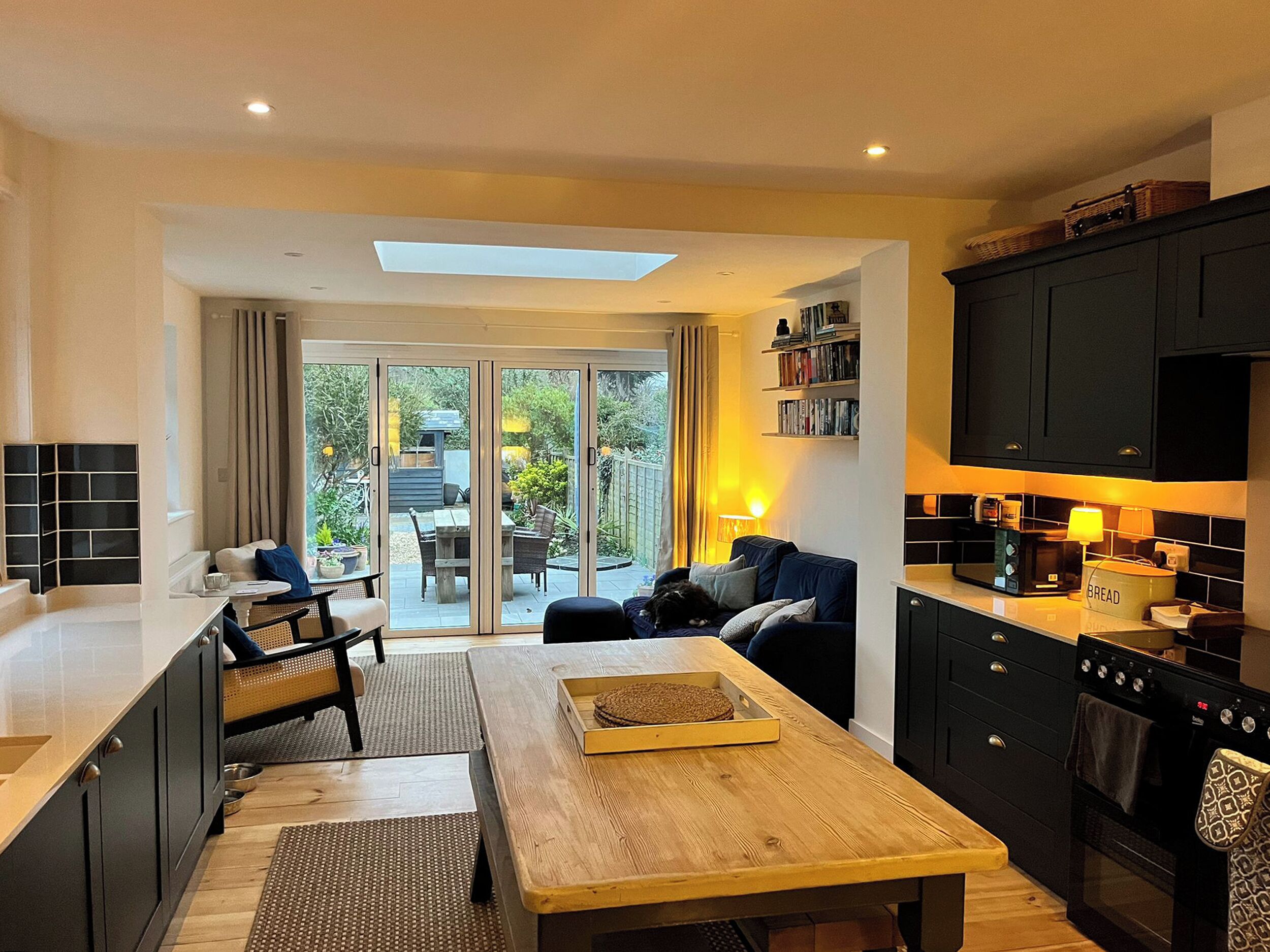 Una cocina moderna con armarios oscuros, una mesa de comedor de madera y vistas al patio exterior.