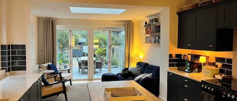 Una cocina moderna con armarios oscuros, una mesa de comedor de madera y vistas al patio exterior.