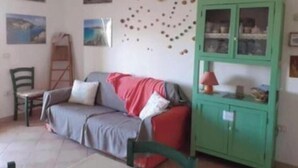 Una habitación con sofá, un armario verde y adornos en la pared.