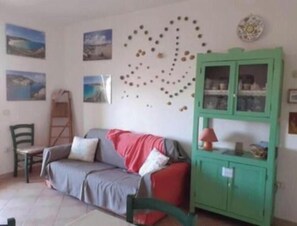 Una habitación con sofá, un armario verde y adornos en la pared.