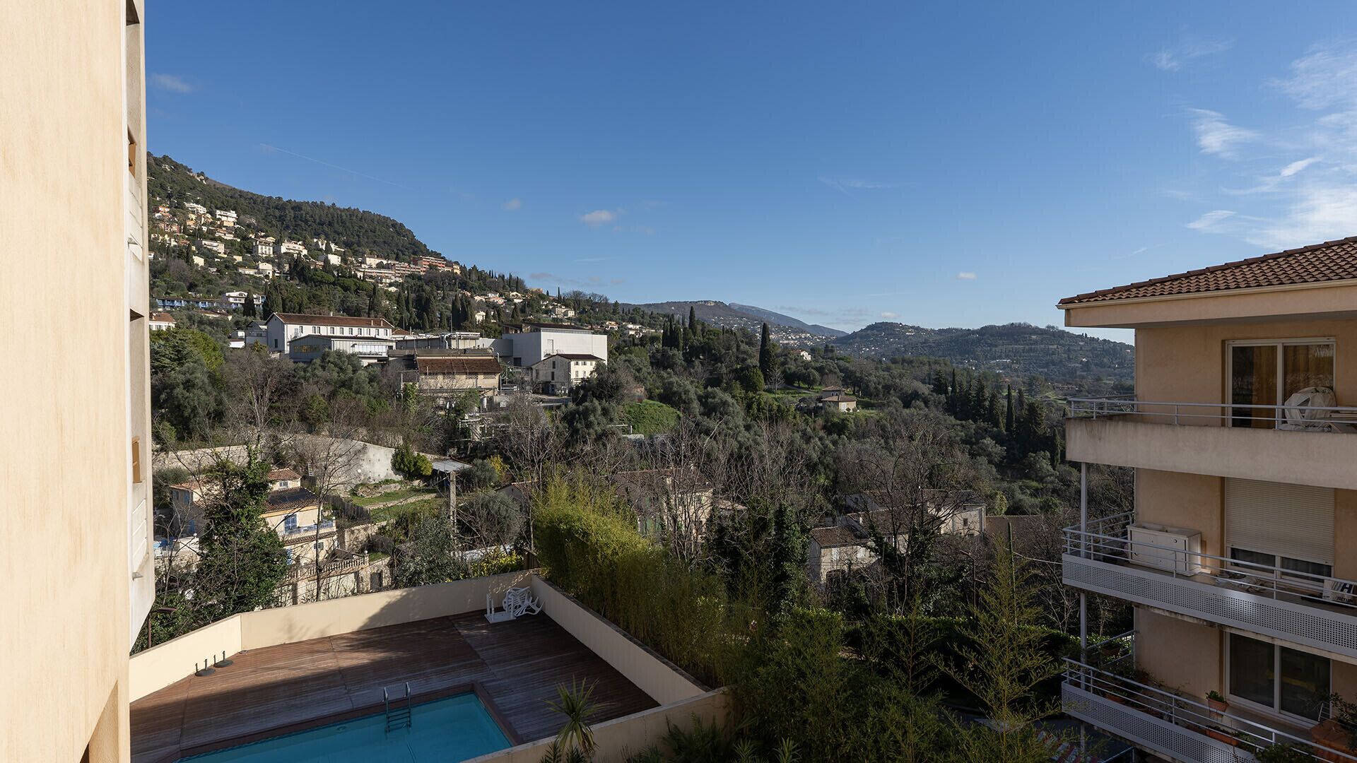 A residential area with a pool, a view of the surrounding hills, and a building with balconies.
