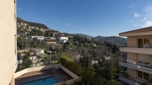 Zona residencial com piscina, vista para as colinas ao redor e um edifício com varandas.