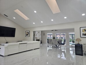 Ein geräumiger Wohnbereich mit einem weißen Sofa, einem Flachbildfernseher und einer Wand im Marmor-Design.