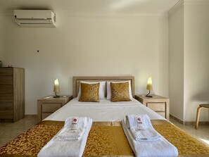 A hotel room with a large bed, two bedside tables with lamps, a wardrobe, and a ceiling air conditioner. - Quarteira Stylish 4 by Homing (Loulé)
