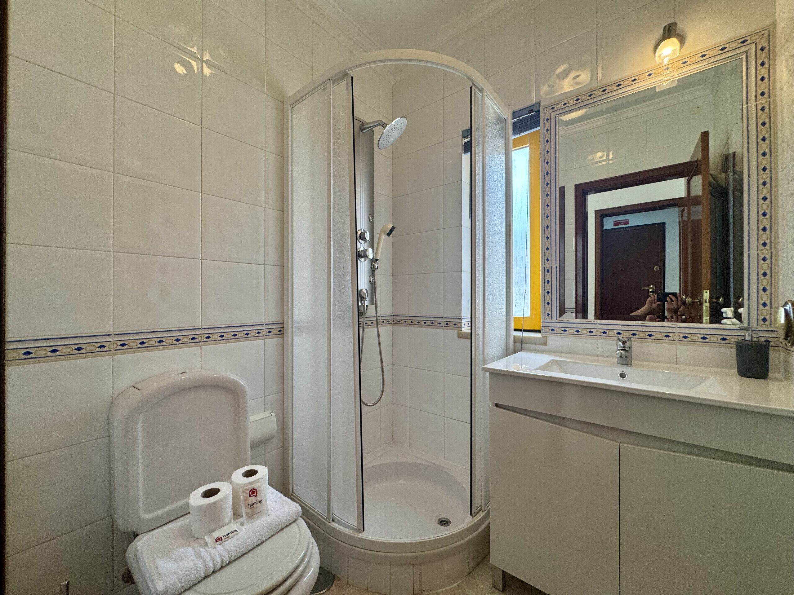 Ein Badezimmer mit Dusche, Toilette, Waschbecken und Spiegel.
