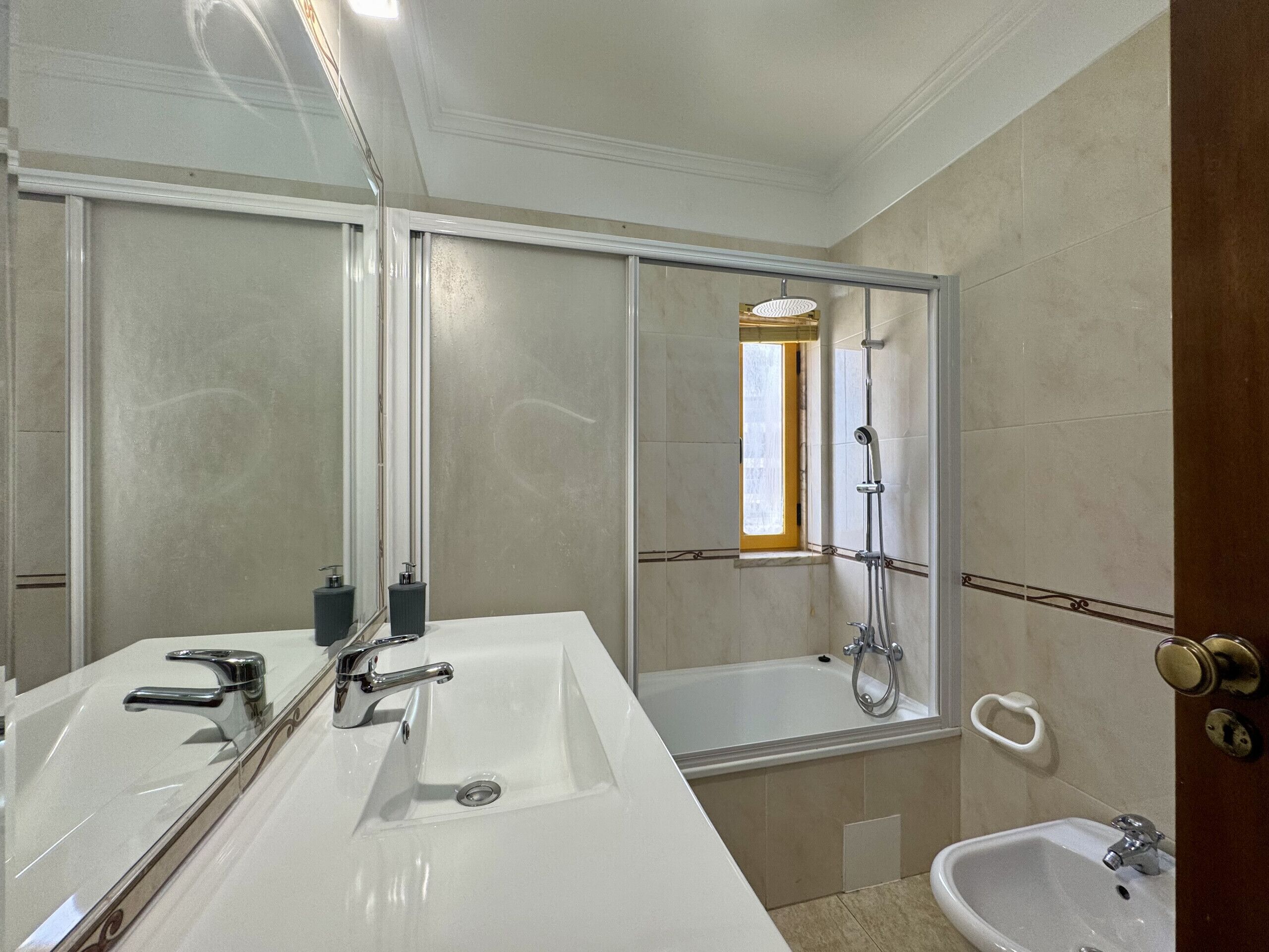 Un baño con un espejo grande, una bañera, una ducha y un lavamanos.