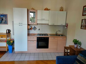 Una cocina compacta con armarios blancos, una estufa a gas, un lavavajillas y un lavamanos.