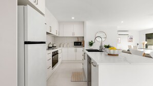 Una cocina moderna con armarios blancos, una isla central, un microondas y un fregadero.