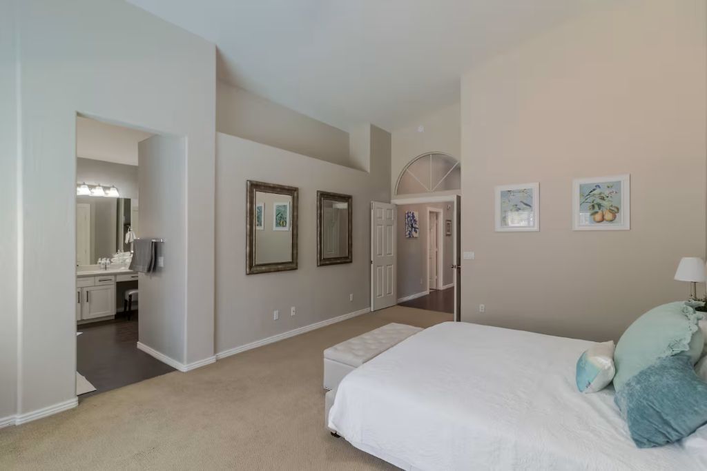 Une chambre avec un lit, une salle de bain avec un lavabo et un couloir.