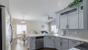 Une cuisine moderne avec des meubles de couleur grise, un lave-vaisselle et un coin repas comprenant une table et des chaises.