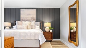 A bedroom with a bed, two nightstands, a mirror, and a large painting on the wall. - Luxe Meridian Retreat •1K+3Q beds • 600+ WiFi • 3 Desks • Games • Prime Location (Meridian)