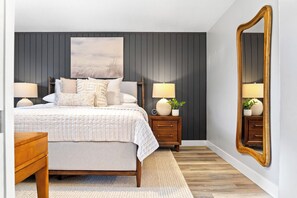 A bedroom with a bed, two nightstands, a mirror, and a large painting on the wall. - Luxe Meridian Retreat •1K+3Q beds • 600+ WiFi • 3 Desks • Games • Prime Location (Meridian)
