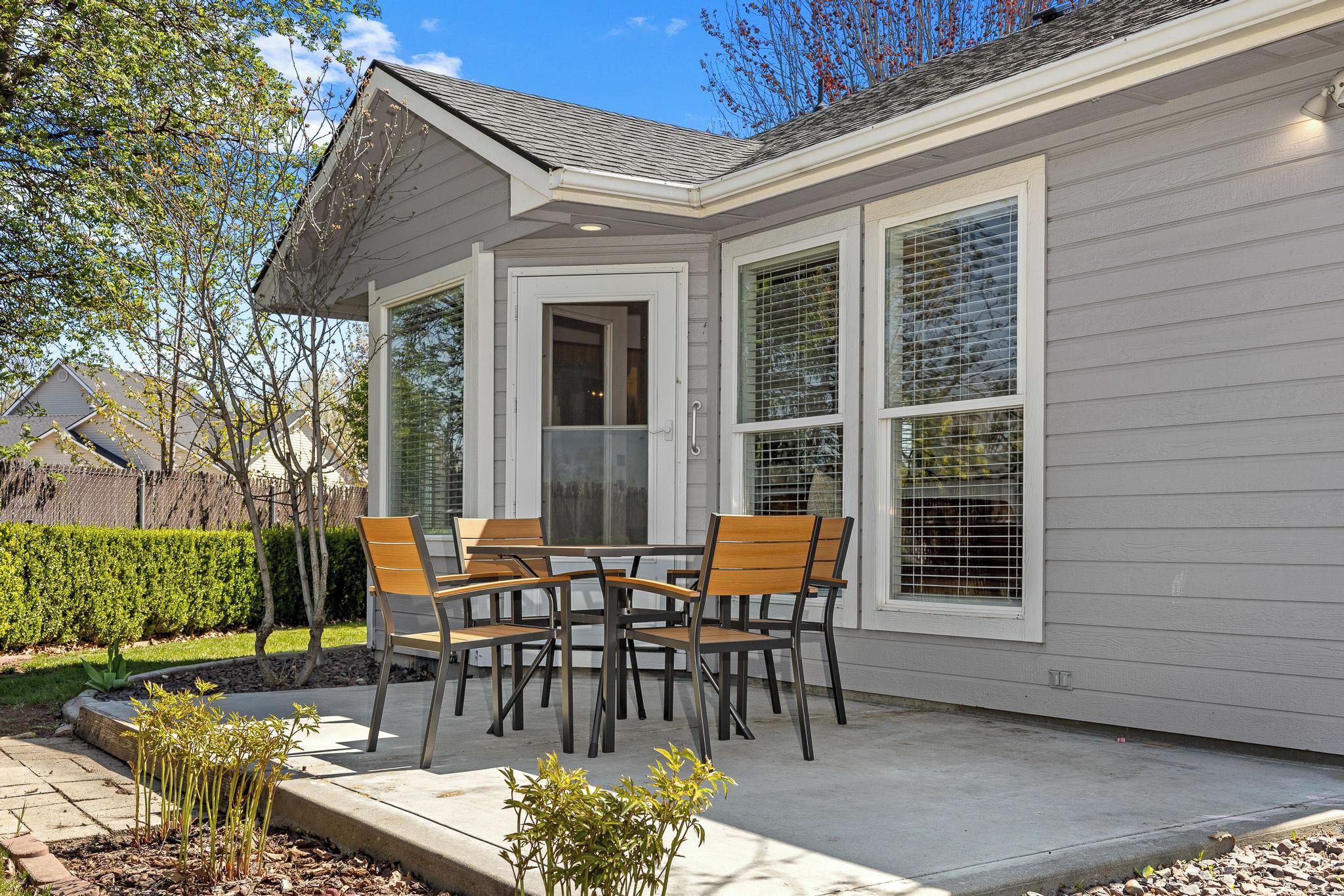A covered patio with a table and chairs, a door, and large windows.