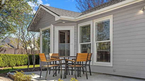 A covered patio with a table and chairs, a door, and large windows. - Luxe Meridian Retreat •1K+3Q beds • 600+ WiFi • 3 Desks • Games • Prime Location (Meridian)
