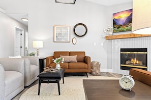A living room with a fireplace, a sofa, a coffee table, and a clock. - Luxe Meridian Retreat •1K+3Q beds • 600+ WiFi • 3 Desks • Games • Prime Location (Meridian)