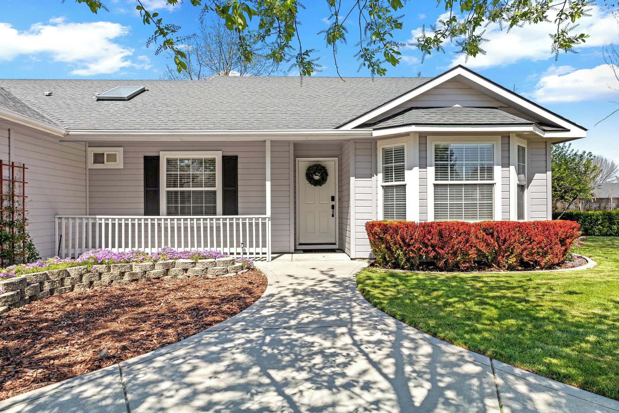 A single-story house with a front porch, a door with a wreath, and a well-maintained lawn.