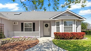 A single-story house with a front porch, a door with a wreath, and a well-maintained lawn. - Luxe Meridian Retreat •1K+3Q beds • 600+ WiFi • 3 Desks • Games • Prime Location (Meridian)