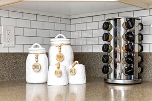 Three white kitchen jars with wooden labels for coffee, flour, and sugar, and a spice rack with black spice containers. - Luxe Meridian Retreat •1K+3Q beds • 600+ WiFi • 3 Desks • Games • Prime Location (Meridian)
