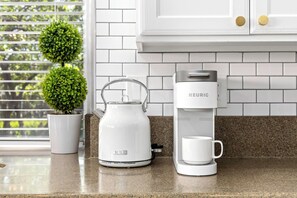 A kitchen with a Keurig coffee maker, a glass carafe, and a potted plant. - Luxe Meridian Retreat •1K+3Q beds • 600+ WiFi • 3 Desks • Games • Prime Location (Meridian)
