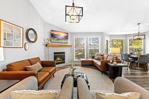 A spacious living room with a fireplace, leather sofas, a dining area, and large windows. - Luxe Meridian Retreat •1K+3Q beds • 600+ WiFi • 3 Desks • Games • Prime Location (Meridian)