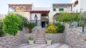 Una casa con fachada de piedra, un porche cubierto y una escalera que lleva a la entrada.