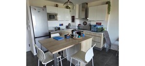 A compact kitchen with a refrigerator, microwave, and a small dining area with a table and chairs. - 2-room apartment with sea view and terrace -near the beach and shops (L'Île-Rousse)