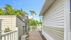 A wooden deck with a white railing, a small shed, and a potted plant. - Lakeside Lily Pad (Fort Myers)