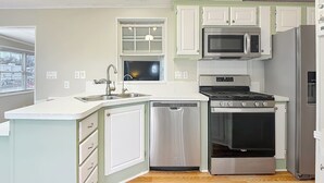 A modern kitchen with a dishwasher, stove, microwave, and a window above the sink. - Lakeside Lily Pad (Fort Myers)