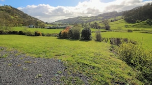 A rural landscape with rolling hills, a clear sky, and a house in the distance. - Spring Bank (Llanfyllin)