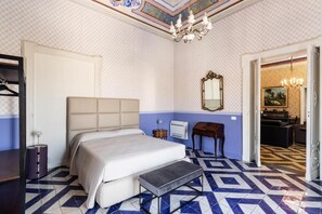 Une chambre à coucher avec un lit, une table de chevet, un miroir, un lustre et un sol à motifs.