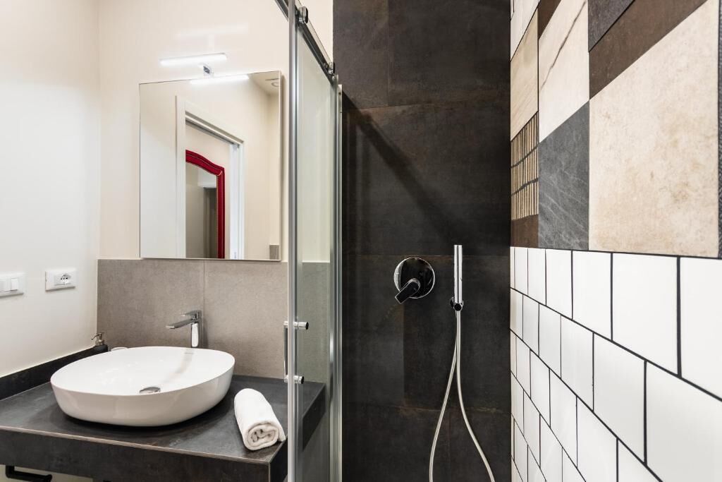Een moderne badkamer met een rond wastafel, een douchecabine van glas en een betegelde muur.