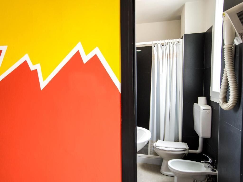 Une salle de bain avec des toilettes blanches, un lavabo et un rideau de douche.