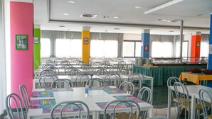 A dining area with multiple tables and chairs, a buffet setup, and large windows with curtains. - hotel elba (Rivazzurra)