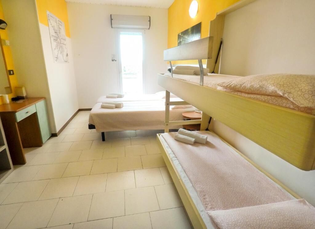 A room with bunk beds, a desk, and a window.