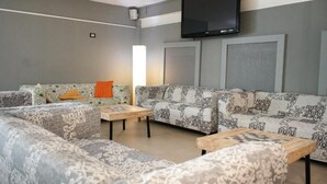A living room with a sofa, two coffee tables, a flat-screen TV mounted on the wall, and a lamp. - hotel elba (Rivazzurra)