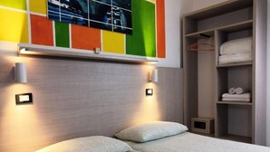A hotel room with a bed, a wardrobe, and a wall-mounted television. - hotel elba (Rivazzurra)