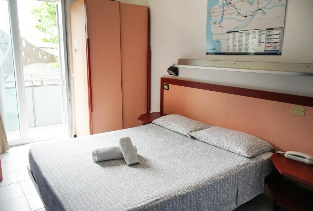 A hotel room with a bed, a map on the wall, and a sliding door.