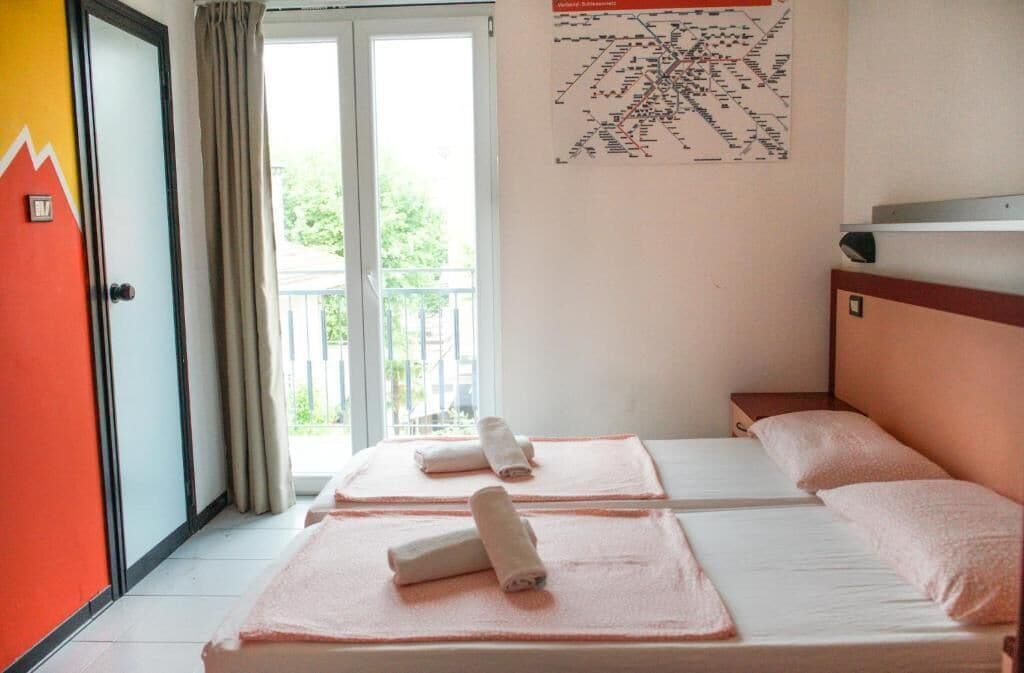 A hotel room with two beds, a balcony, and a map on the wall.