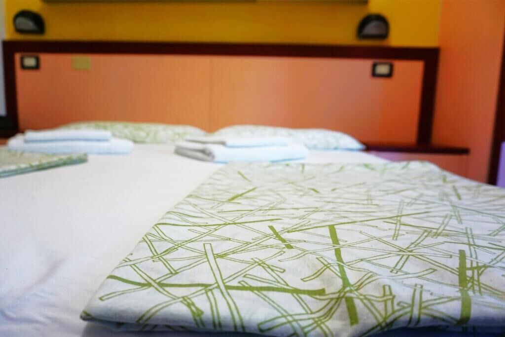 Una camera d'albergo con un letto, cuscini e una testiera.